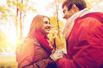 Image showing happy couple with maple leaves in autumn park