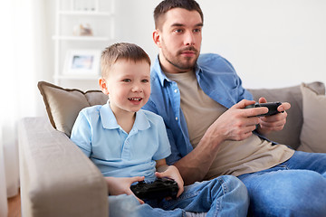 Image showing father and son playing video game at home