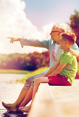 Image showing grandfather and grandson sitting on river berth