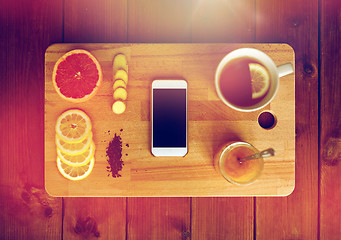 Image showing smartphone with cup of lemon tea, honey and ginger