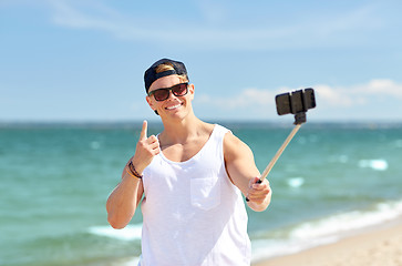 Image showing man with smartphone selfie stick on summer beach