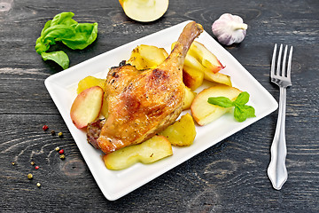Image showing Duck leg with apple and potatoes in plate on black board