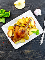 Image showing Duck leg with apple and potatoes in plate on board top