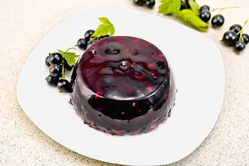 Image showing Jelly from black currant with berries in plate on granite table