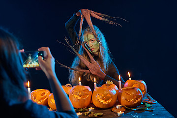 Image showing Girl capturing photo of Halloween woman with her smart phone