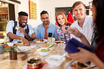 Image showing happy friends with money paying bill at restaurant