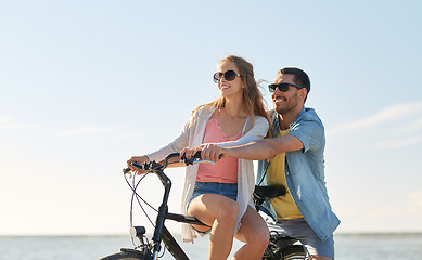 Image showing happy young couple riding bicycles at seaside
