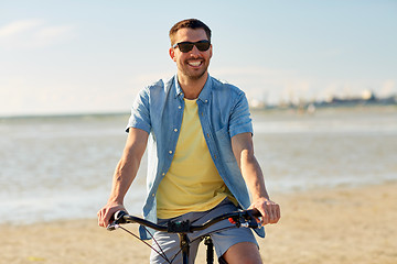 Image showing happy man riding bicycle along summer beach