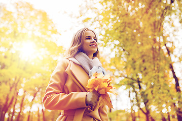 Image showing beautiful woman with maple leaves in autumn park