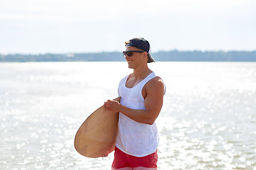 Image showing happy young man with skimboard on summer beach