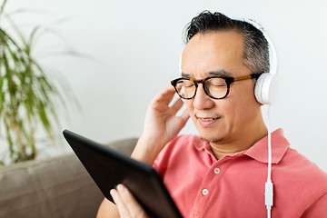 Image showing man with tablet pc and headphones at home