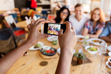 Image showing friends taking picture by smartphone at restaurant