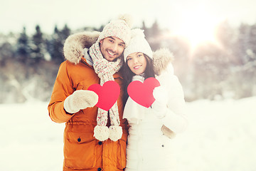 Image showing happy couple with red hearts over winter landscape