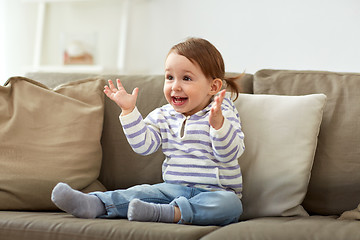 Image showing happy smiling baby girl sitting on sofa at home