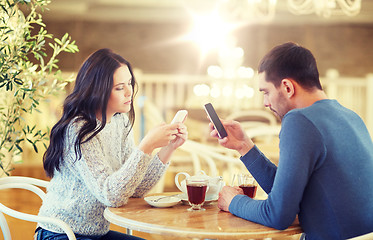 Image showing couple with smartphones drinking tea at cafe