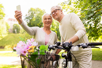 Image showing senior couple with bicycles taking selfie at park