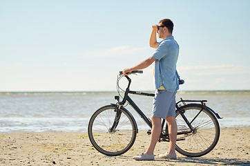 Image showing happy young man with bicycle on beach 