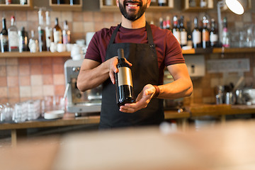 Image showing happy man or bartender with bottle of wine at bar