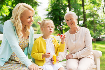 Image showing happy family blowing soap bubbles at park