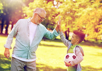 Image showing old man and boy with soccer ball making high five