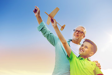 Image showing senior man and boy with toy airplane over sky