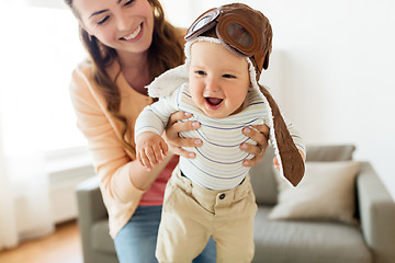 Image showing happy mother with baby wearing pilot hat at home