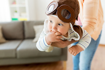 Image showing happy mother with baby wearing pilot hat at home