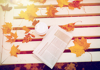 Image showing newspaper and coffee cup on bench in autumn park