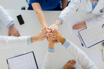 Image showing group of doctors making high five at table