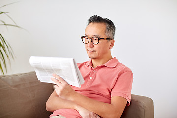 Image showing happy man in glasses reading newspaper at home