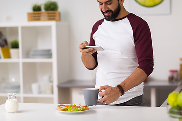 Image showing man with smartphone and coffee eating at home