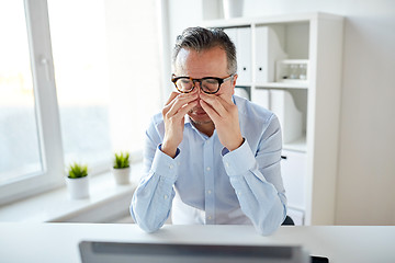 Image showing tired businessman in glasses with laptop at office