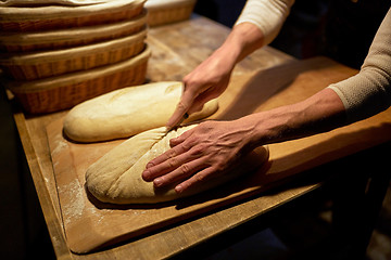 Image showing baker making bread and cutting dough at bakery