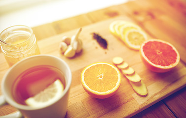 Image showing ginger tea with honey, citrus and garlic on wood