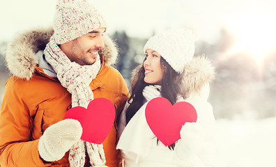 Image showing happy couple with red hearts over winter landscape