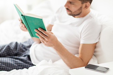 Image showing man reading book in bed at home