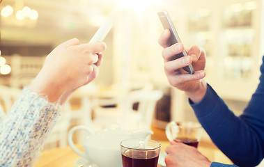 Image showing close up of couple with smartphones at cafe