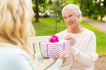 Image showing daughter giving present to senior mother at park