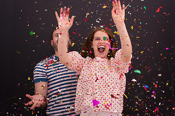 Image showing couple blowing confetti in the air isolated over gray