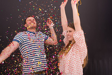 Image showing couple blowing confetti in the air isolated over gray