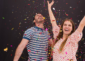 Image showing couple blowing confetti in the air isolated over gray