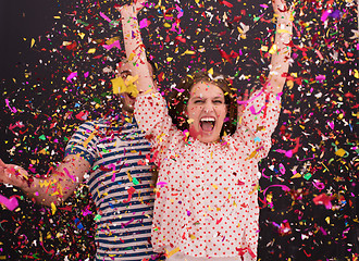 Image showing couple blowing confetti in the air isolated over gray