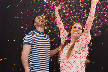 Image showing couple blowing confetti in the air isolated over gray