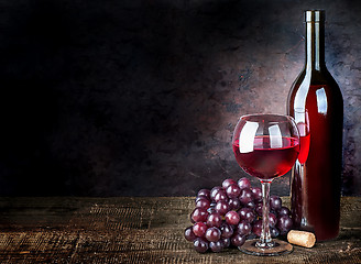 Image showing Glass of red wine with grapes and bottle