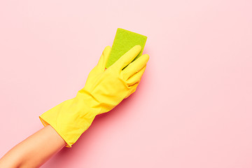 Image showing The woman\'s hand cleaning on a pink background. Cleaning or housekeeping concept