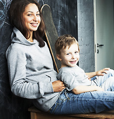 Image showing little cute boy with young teacher in classroom studying at blac