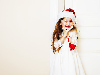 Image showing little cute girl in santas red hat waiting for Christmas gifts. 