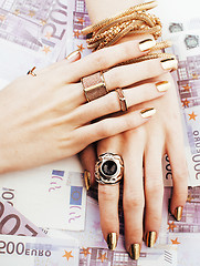 Image showing hands of rich woman with golden manicure and many jewelry rings 