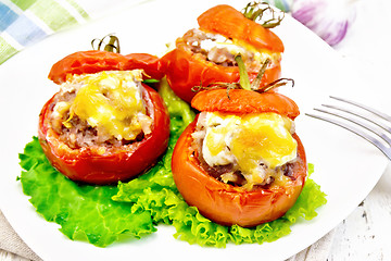 Image showing Tomatoes stuffed with meat and rice with lettuce in plate on boa