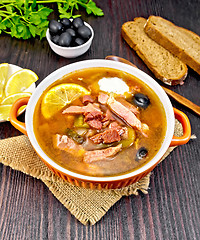 Image showing Solyanka with lemon and spoon in bowl on dark board